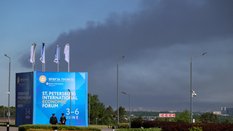 Policjanci stoją przed banerem i flagami z logo Międzynarodowego Forum Ekonomicznego w Petersburgu (