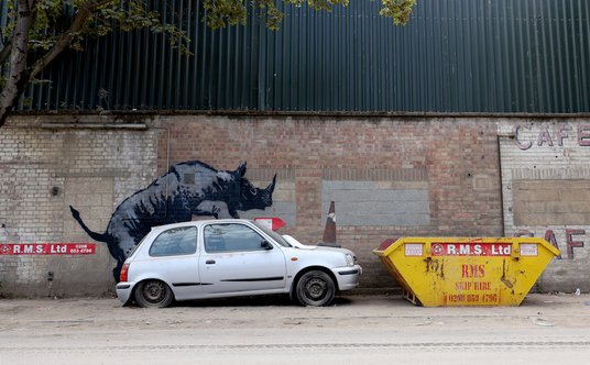 Ósma praca z nowego cyklu Banksy'ego przedstawia nosorożca wdrapującego się na porzucony samochód.