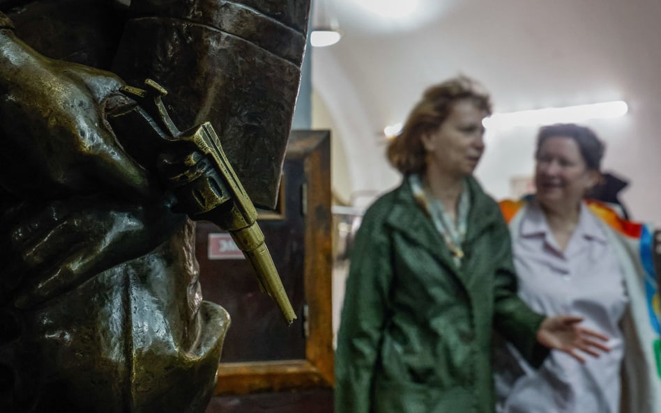 Dwie Rosjanki mijają fragment rzeźby przedstawiajacy rewolwer Nagant, stacja metra Płoszczad´ Riewol