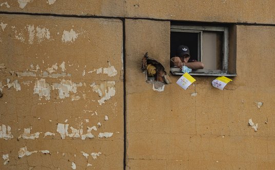 Mężczyzna trzyma watykańską flagę przed spotkaniem papieża Franciszka ze społecznością romską w Kosz