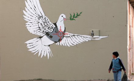 Betlejem na Zachodnim Brzegu. Palestyński chłopiec ogląda pracę Banksy’ego, brytyjskiego artysty uli