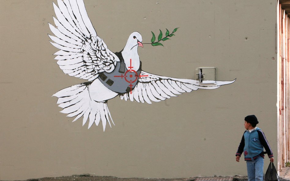 Betlejem na Zachodnim Brzegu. Palestyński chłopiec ogląda pracę Banksy’ego, brytyjskiego artysty uli