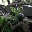 Ukraiński artylerzysta używa gałęzi do kamuflażu pojazdu na linii frontu w pobliżu Bachmutu