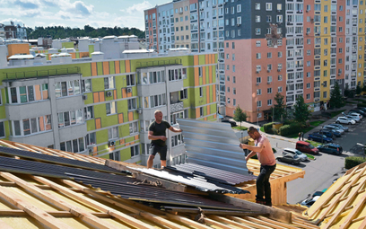 Robotnicy w Irpieniu w obwodzie kijowskim naprawiają dach bloku uszkodzonego w czasie rosyjskiego os