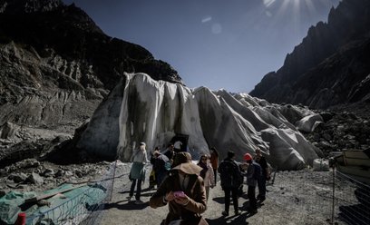Wejście do jaskini w lodowcu Mer de Glace w masywie Mont Blanc przykryte specjalną plandeką, by spow