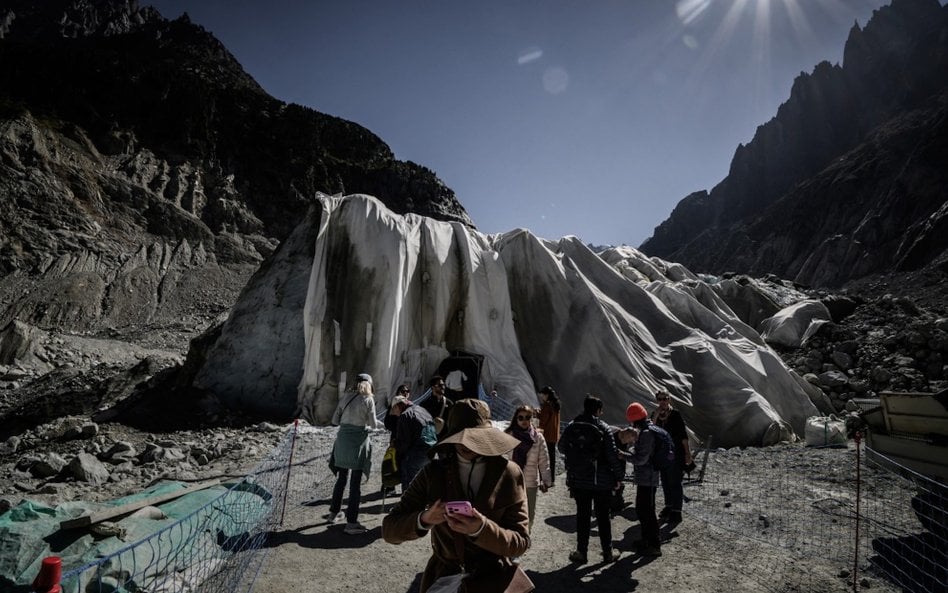 Wejście do jaskini w lodowcu Mer de Glace w masywie Mont Blanc przykryte specjalną plandeką, by spow