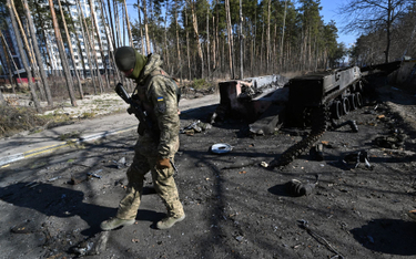 Ukraińśki żołnierz przy wraku zniszczonego rosyjskiego wozu bojowego