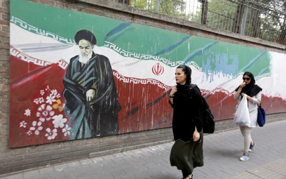 Przechodnie w Teheranie na tle muralu na ogrodzeniu byłej ambasady Stanów Zjednoczonych.