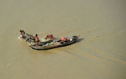 Rybak próbujący zakotwiczyć swoją łódź na indyjskiej rzece Ganges.