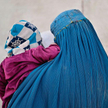 Kabul, 3 listopada. Afganka, całkowicie ukryta pod burką, przemierza ulicę z dzieckiem na rękach