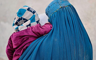 Kabul, 3 listopada. Afganka, całkowicie ukryta pod burką, przemierza ulicę z dzieckiem na rękach
