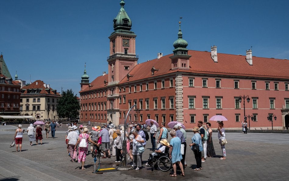 Turyści korzystają z mgiełki wodnej na Placu Zamkowym na Starym Mieście w Warszawie, w czasie wysoki