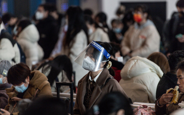 Pasażerka w masce i przyłbicy na dworcu w Wuhan