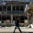 Donbas. Mężczyzna mija budynek zniszczony podczas ostrzału