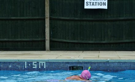 Pani Anne Whitman pływa w podgrzewanym basenie po oddaniu głosu w komisji wyborczej (w głębi) w Arun