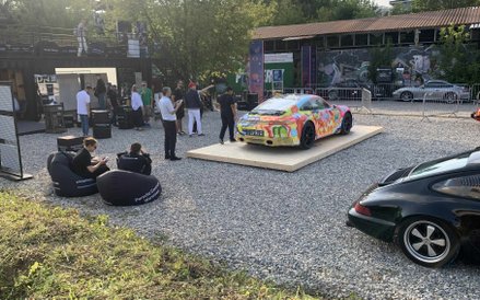 Unikatowe Porsche z karoserią ozdobioną kolorowym, artystycznym wzorem, eksponowane na drewnianej pl