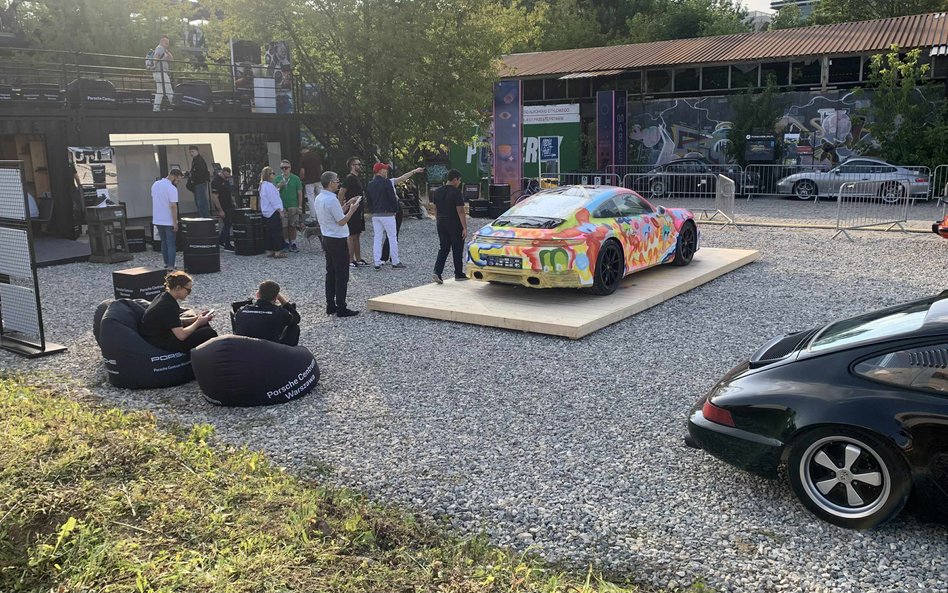 Unikatowe Porsche z karoserią ozdobioną kolorowym, artystycznym wzorem, eksponowane na drewnianej pl