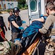 Ratownicy medyczni wnoszą do karetki cywila ranionego przez rosyjską bombę klastrową zrzuconą na Bac