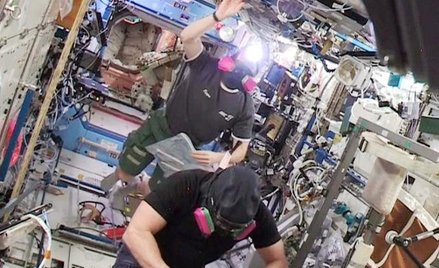 Astronauci Barry WiImore i Terry Virts wracają w maskach przeciwgazowych do amerykańskiej części sta