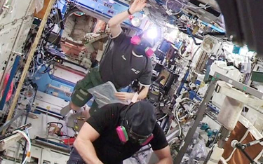 Astronauci Barry WiImore i Terry Virts wracają w maskach przeciwgazowych do amerykańskiej części sta