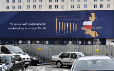 Wielkoformatowy baner o przyczynach inflacji na fasadzie siedziby Narodowego Banku Polskiego
