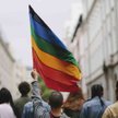 Mężczyzna unosi w górę tęczową flagę (zdjęcie ilustracyjne)