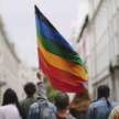 Mężczyzna unosi w górę tęczową flagę (zdjęcie ilustracyjne)