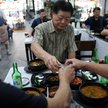 Koreańczycy wznoszący toast podczas jedzenia gulaszu z psiego mięsa