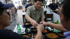 Koreańczycy wznoszący toast podczas jedzenia gulaszu z psiego mięsa
