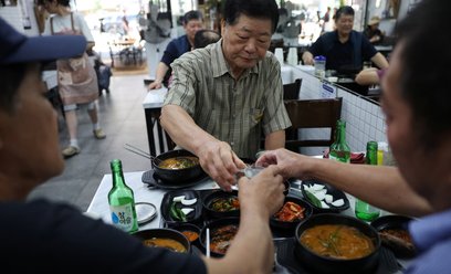 Koreańczycy wznoszący toast podczas jedzenia gulaszu z psiego mięsa