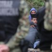 Grupa uchodźców i straż graniczna niedaleko granicą Białorusi z Polską (zdjęcie ilustracyjne)