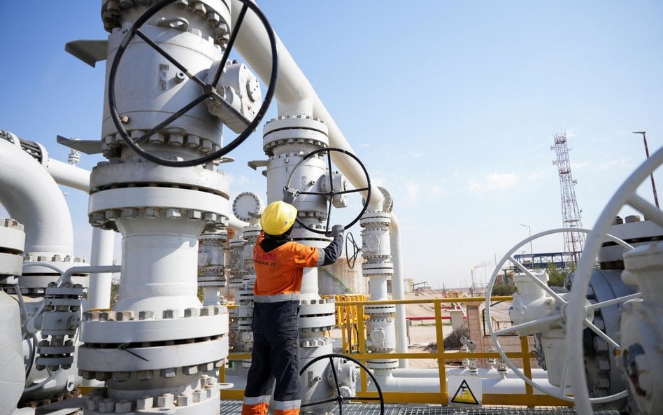 Pracownik obsługuje zawory na polu naftowym Rumaila, ponieważ kraj ogranicza produkcję ropy o prawie
