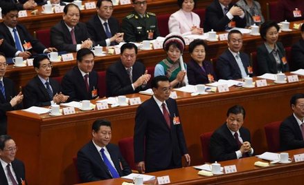 Chińscy parlamentarzyści, niektórzy w strojach ludowych, słuchają przemówienia premiera Li Keqiang