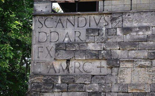 Fasada z inskrypcją: SCANDIVS DD AR FX TAMRC+. To ma oznaczać: „Pnący się przebudował świątynię maso