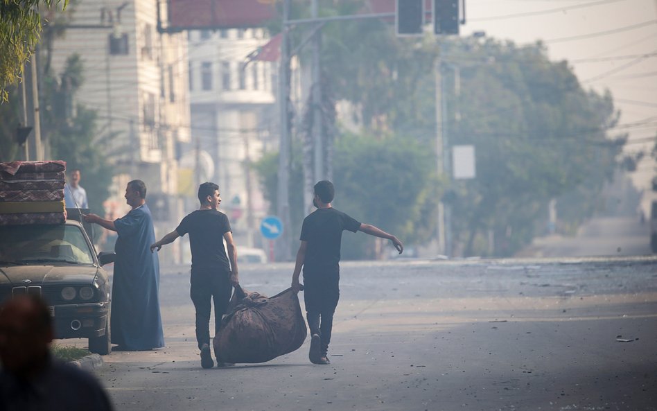 Palestyńczycy opuszczają domostwa w pobliżu wieży Al-Watan w mieście Gaza, po jej zniszczeniu w wyni