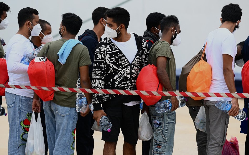 Migranci w kolejce przed wejściem na pokład łodzi w porcie na wyspie Lampedusa.