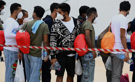 Migranci w kolejce przed wejściem na pokład łodzi w porcie na wyspie Lampedusa.