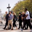 Amerykańscy katolicy niosą na zmianę drewniany krzyż podczas procesji Drogi Krzyżowej niedaleko kopu