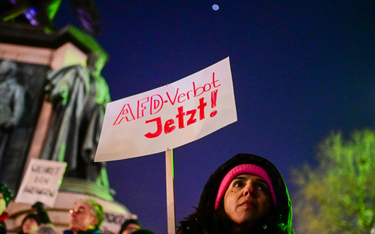 Kobieta trzyma plakaty z napisem „Zakaz AFD” podczas demonstracji przeciwko prawicowemu ekstremizmow
