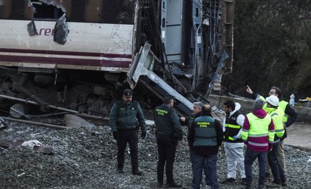 Członkowie hiszpańskiej Gwardii Cywilnej i zespołu operatora kolejowego Adif stoją przy wraku pociąg