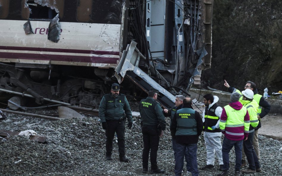 Członkowie hiszpańskiej Gwardii Cywilnej i zespołu operatora kolejowego Adif stoją przy wraku pociąg