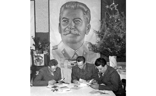 Portret Józefa Stalina obok choinki... Żołnierze Czechosłowackiej Armii Ludowej czytają kartki świąt