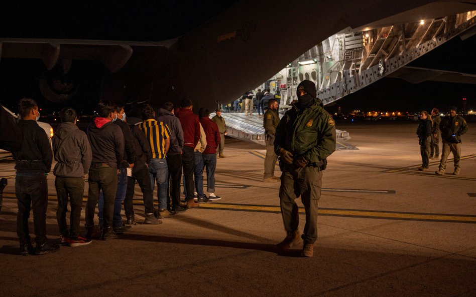 Agenci Służby Celnej i Ochrony Granic USA nadzorują lokowanie zatrzymanych migrantów na pokład samol