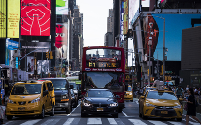 Auto Ubera między charakterystycznymi żółtymi taksówkami w Nowym Jorku w pobliżu Times Square. Władz