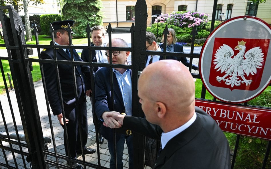 Sędzia TK Marcin Dziurda (C) wita się przez furtkę z sędzią Bartłomiejem Starostą, członkiem nowej K