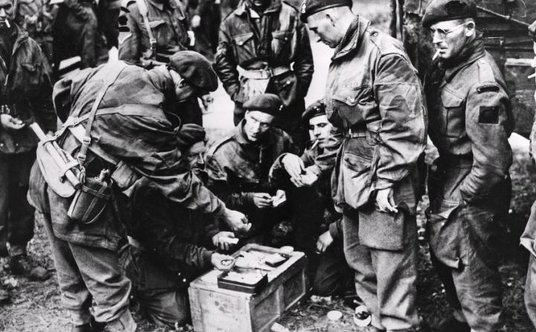 Żołnierze brytyjscy dzielą się zapasami czekolady i papierosów. Zdjęcie wykonane w okolicach Arnhem 