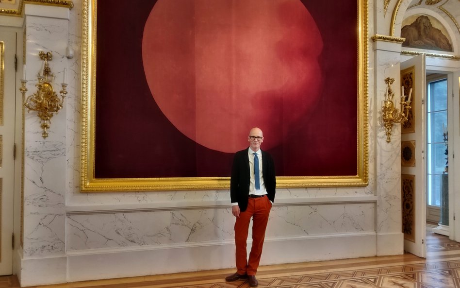 Nicolas Grospierre na tle czerwonej holografii w Sali Salomona
