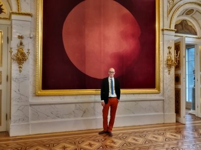 Nicolas Grospierre na tle czerwonej holografii w Sali Salomona