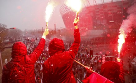 Uczestnicy Marszu Niepodległości zapalają race przed Stadionem Narodowym