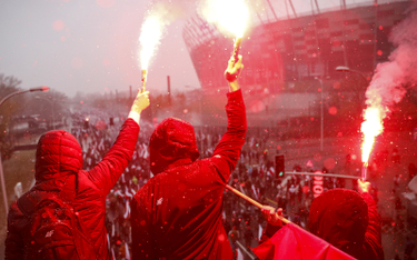 Uczestnicy Marszu Niepodległości zapalają race przed Stadionem Narodowym
